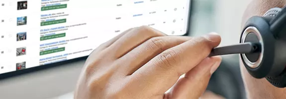 Person mit Headset betrachtet die Joomla-Benutzeroberfläche auf einem Monitor und gibt telefonisch Joomla Support