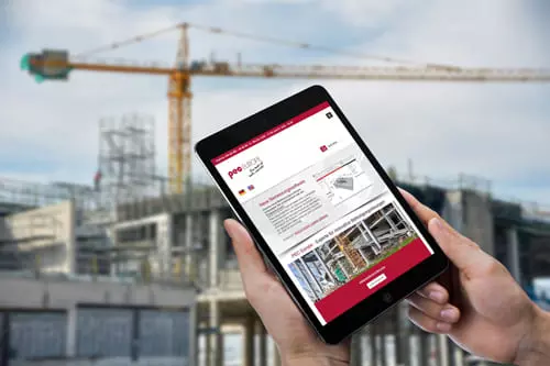 Person hält ein Tablet mit der Website von PEC Europe GmbH, im Hintergrund eine Baustelle mit einem Kran