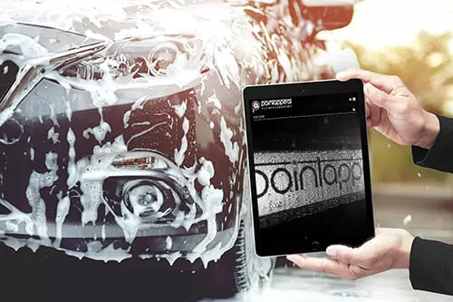 Tablet mit Paintappeal Onlineshop vor einem Auto in der Autowaschanlage