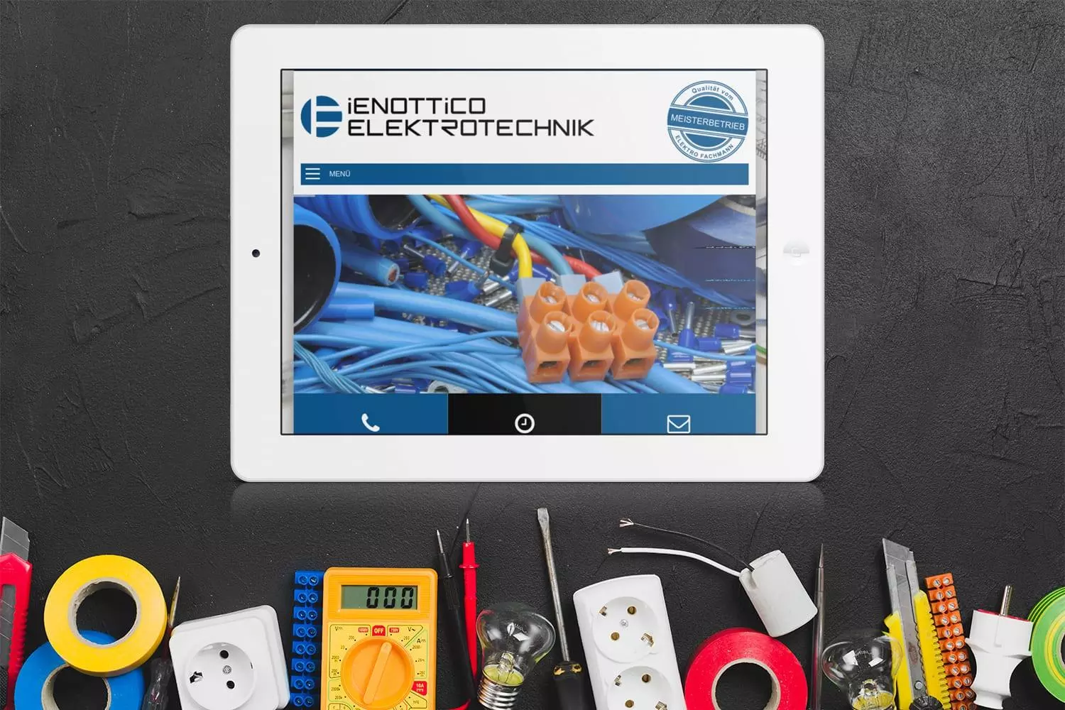 Tablet zeigt die Website von Ienottico Elektrotechnik, umgeben von verschiedenen Elektronikwerkzeugen