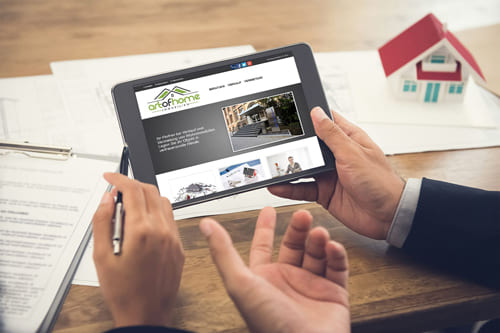 Webdesign für die Immobilien-Website Art of Home Immobilien in Mülheim an der Ruh Zwei Personen betrachten eine Immobilien-Website auf einem Tablet bei einer Besprechung