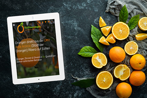 Onlineshop Natürlich Sizilien - Giuseppe Musso mit Template Nova Tablet zeigt den Onlineshop von Natürlich Sizilien vor einem Hintergrund mit frischen Orangen