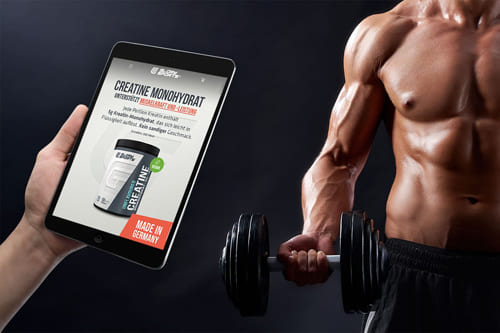 Referenz Onlineshop Glorysports für Fitnesszubehör Tablet zeigt den Onlineshop von Glorysports für Fitnesszubehör vor einem muskulösen Mann mit Hantel