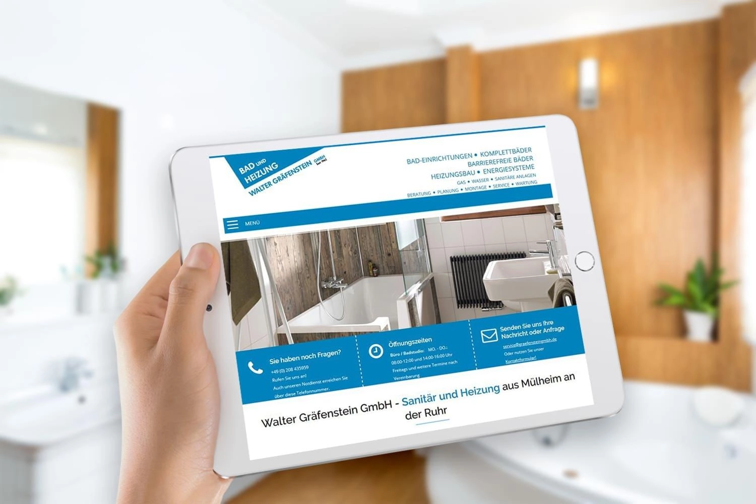 Person hält ein Tablet mit der Joomla Website von Walter Gräfenstein GmbH, im Hintergrund ein modernes Badezimmer